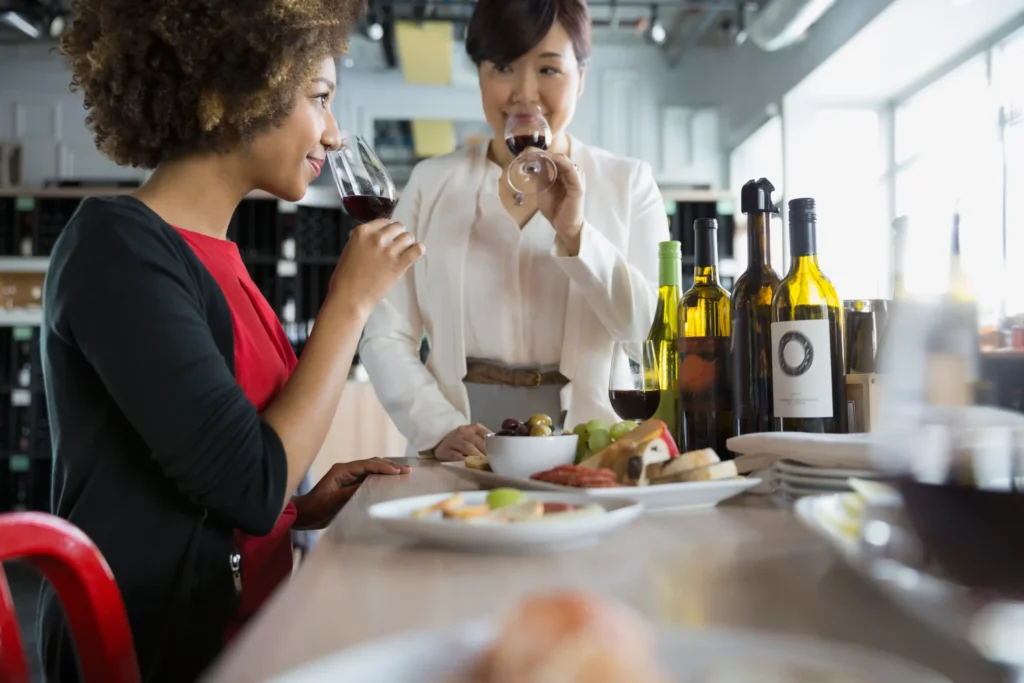 Two women enjoying a wine tasting session with bottles and snacks, reflecting lifestyle storytelling used by a social media agency for restaurants.