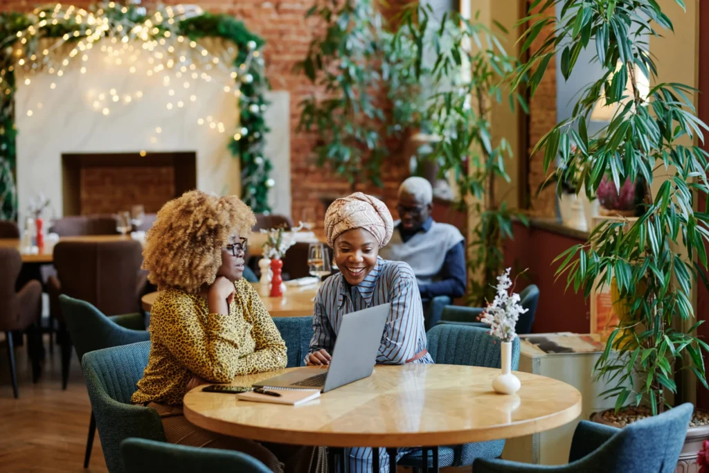 Two women discussing restaurant marketing plans on a laptop inside a cozy café, showcasing collaboration with a digital marketing agency for restaurants.