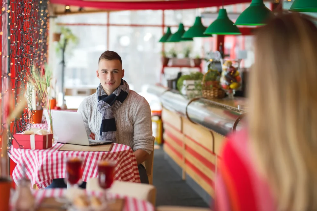 Man using a laptop at a modern café, symbolizing digital engagement and success with a digital marketing agency for restaurants.