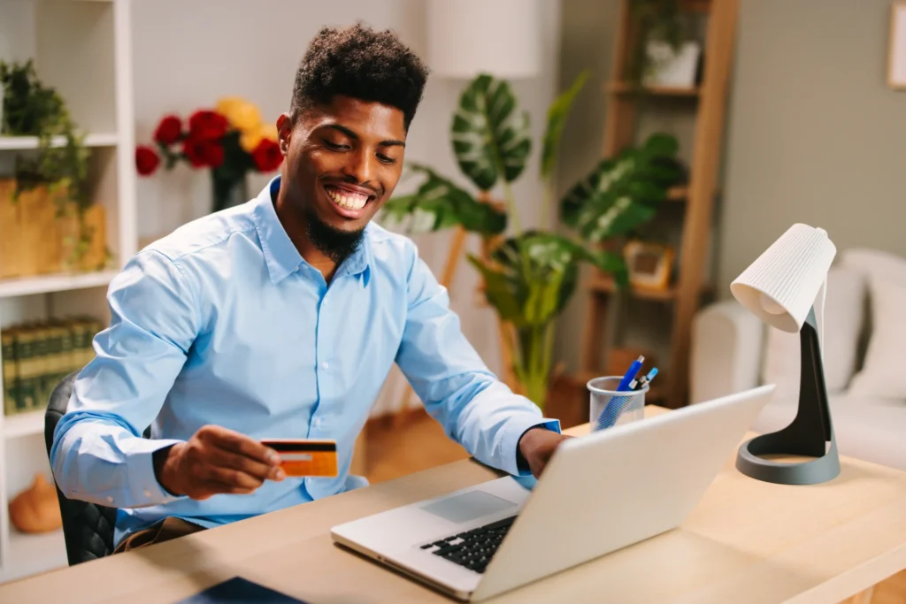 A happy man using a laptop and credit card at home, symbolizing customer engagement through effective local SEO for ecommerce.