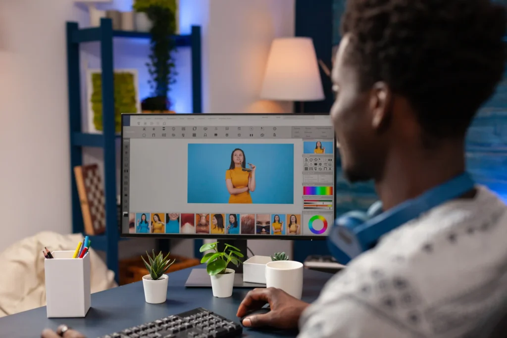 Man editing images on a computer in a home office, showing creative work involved in freelance digital marketing services like content creation and design.