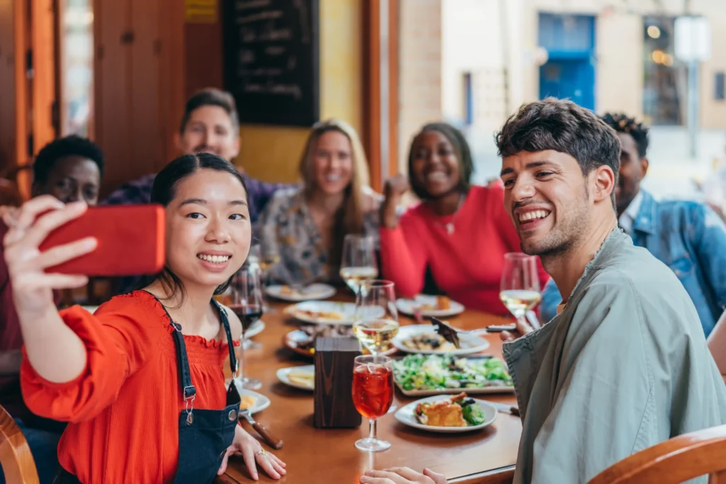 A group of friends taking a selfie while dining together, representing restaurant advertising ideas that focus on social media engagement.