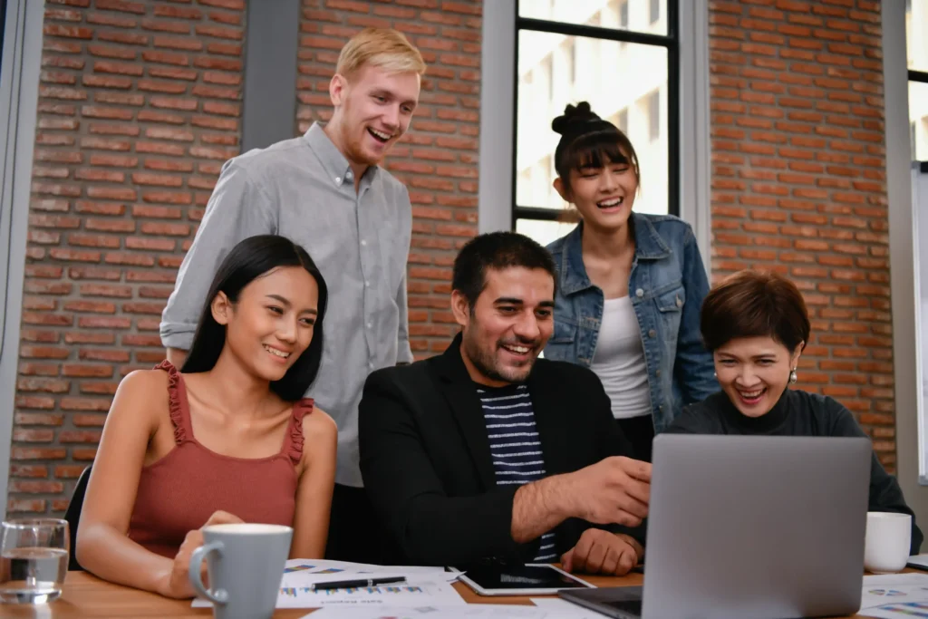 Team collaborating on a project at a digital website agency while reviewing creative work on a laptop.