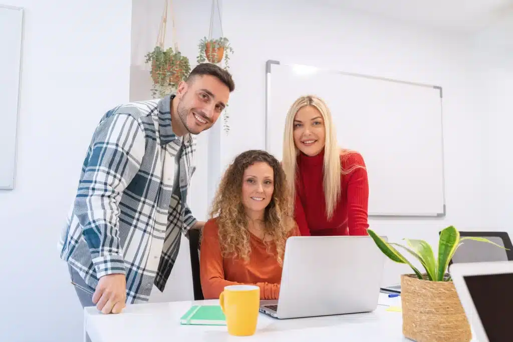 Three team members smiling and working together at a digital web agency, planning brand and website strategies.