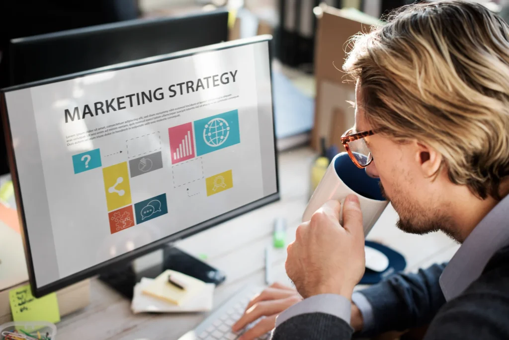 Man reviewing a marketing strategy dashboard on a computer while holding a coffee mug, symbolizing strategic planning within freelance digital marketing services.
