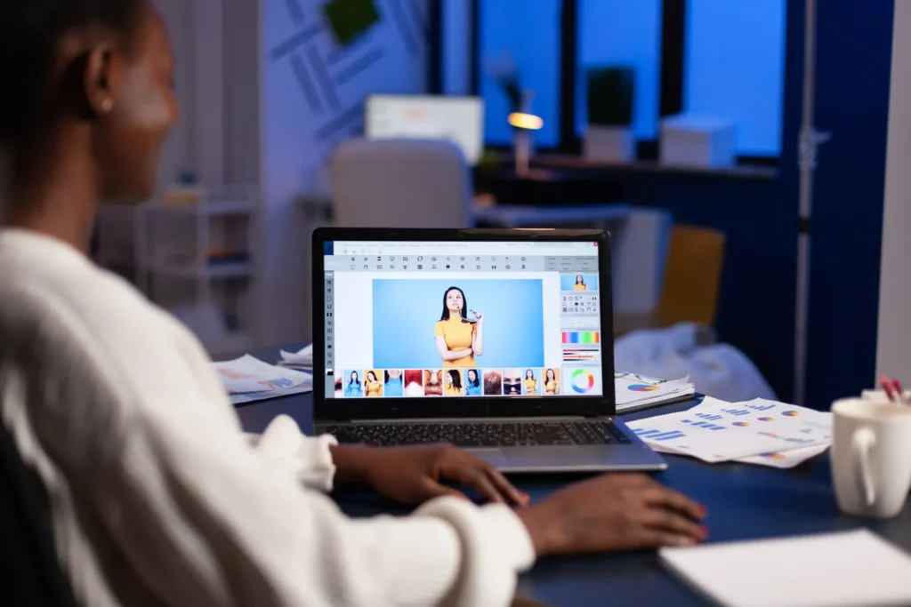 Designer editing graphics on a laptop, showcasing creative content production within an online digital marketing company.