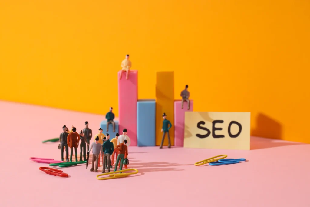 Miniature figures gathered around colorful bar graphs and an SEO label, symbolizing community-focused Local SEO management.