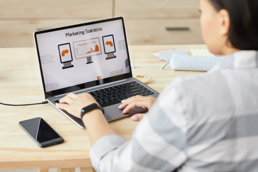 Woman reviewing marketing statistics on a laptop, illustrating data-driven design strategies used in the best digital agency websites.