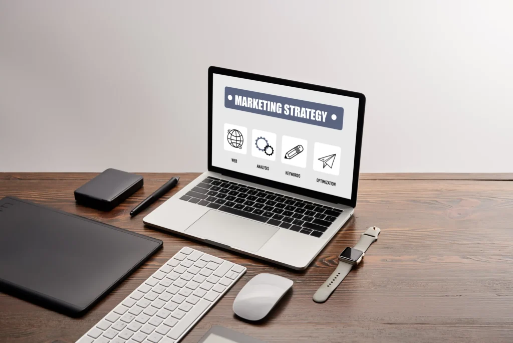 digital marketing agency website planning workspace with laptop displaying marketing strategy and optimization icons
