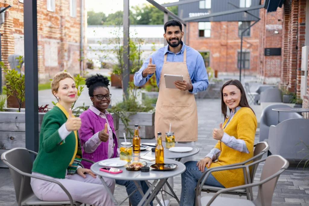 Customers dining outdoors and giving a thumbs up, showcasing restaurant advertising ideas centered on customer experience and reviews.