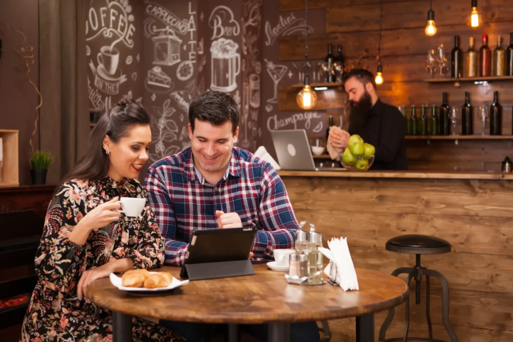 Digital marketing for restaurant visibility as customers use a tablet to browse menus, reviews, and dining options inside a café