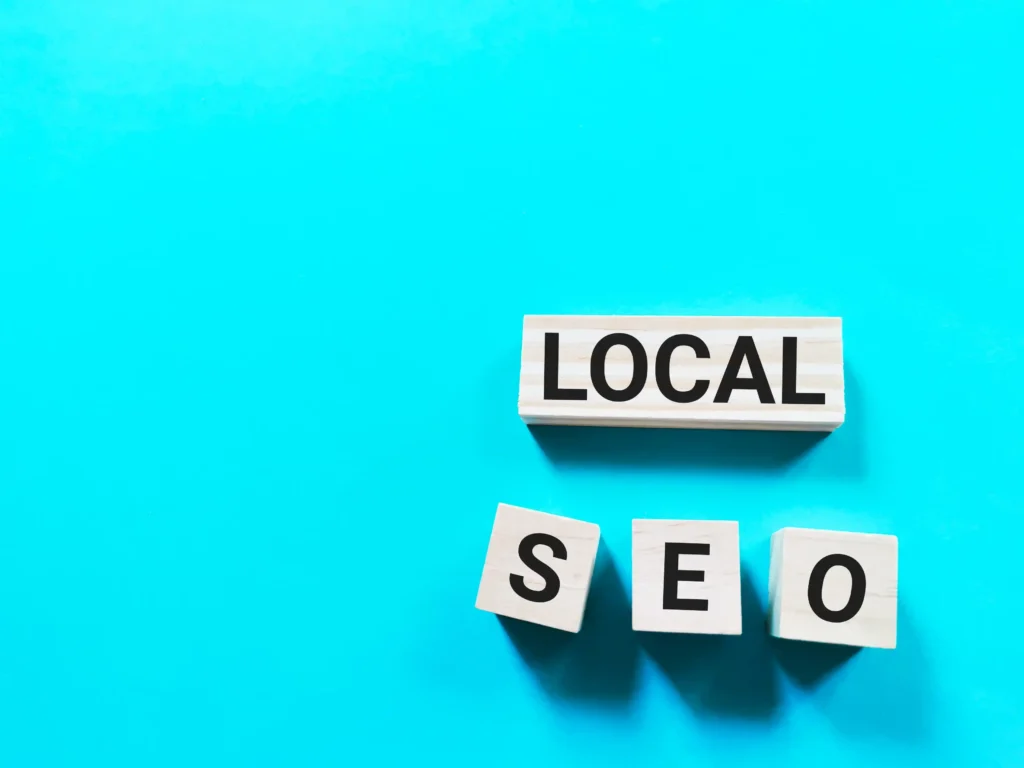 Wooden cubes spelling out local SEO on a bright blue background, symbolizing local SEO link building foundations.