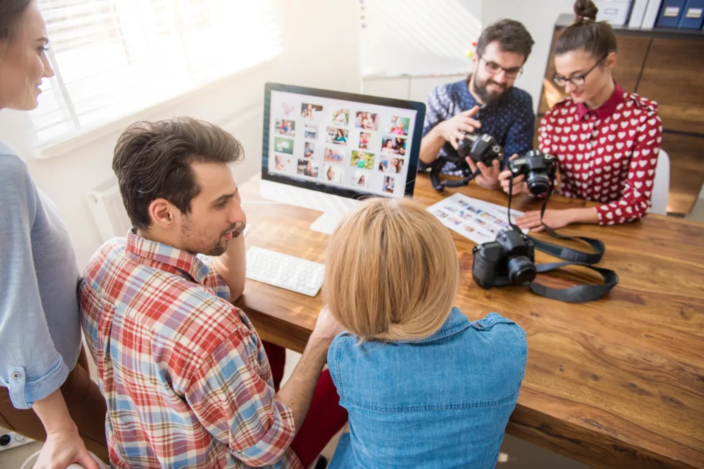 Creative agency team reviewing photography and design layouts, reflecting visual storytelling used in the best marketing agency websites.