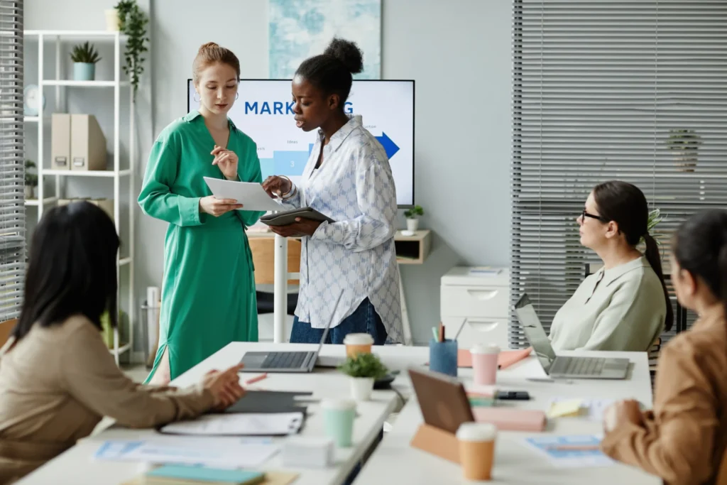 Marketing professionals in a meeting at an online digital marketing agency discussing strategy, performance metrics, and campaign direction.