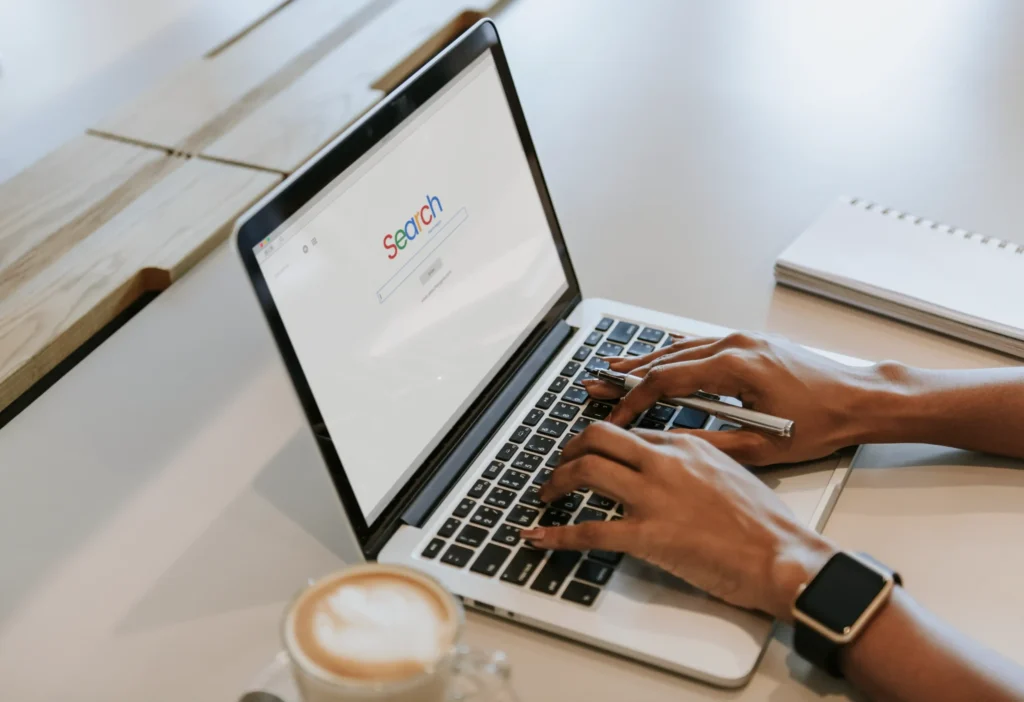 A person typing on a laptop with a search engine screen open, representing how seo local services improve online visibility.