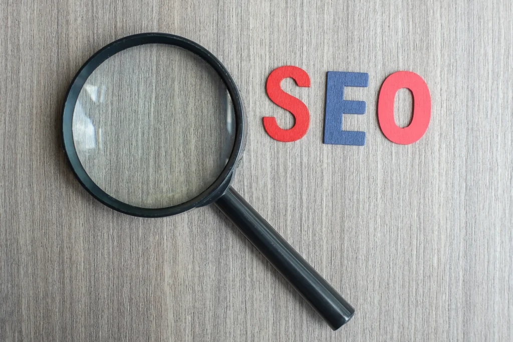 Magnifying glass beside bold SEO letters on a wooden surface, illustrating search visibility in Local SEO management.